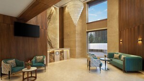 A spacious lobby with a modern design, featuring a large chandelier, a reception desk, and a seating area with sofas and chairs. - The Fern Residency Mumbai, Mira Road, Series by Marriott (Mumbai)