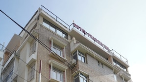 Een meerhoog hotel met balkons en een bord waarop staat: HOTEL PRANJAL INN.