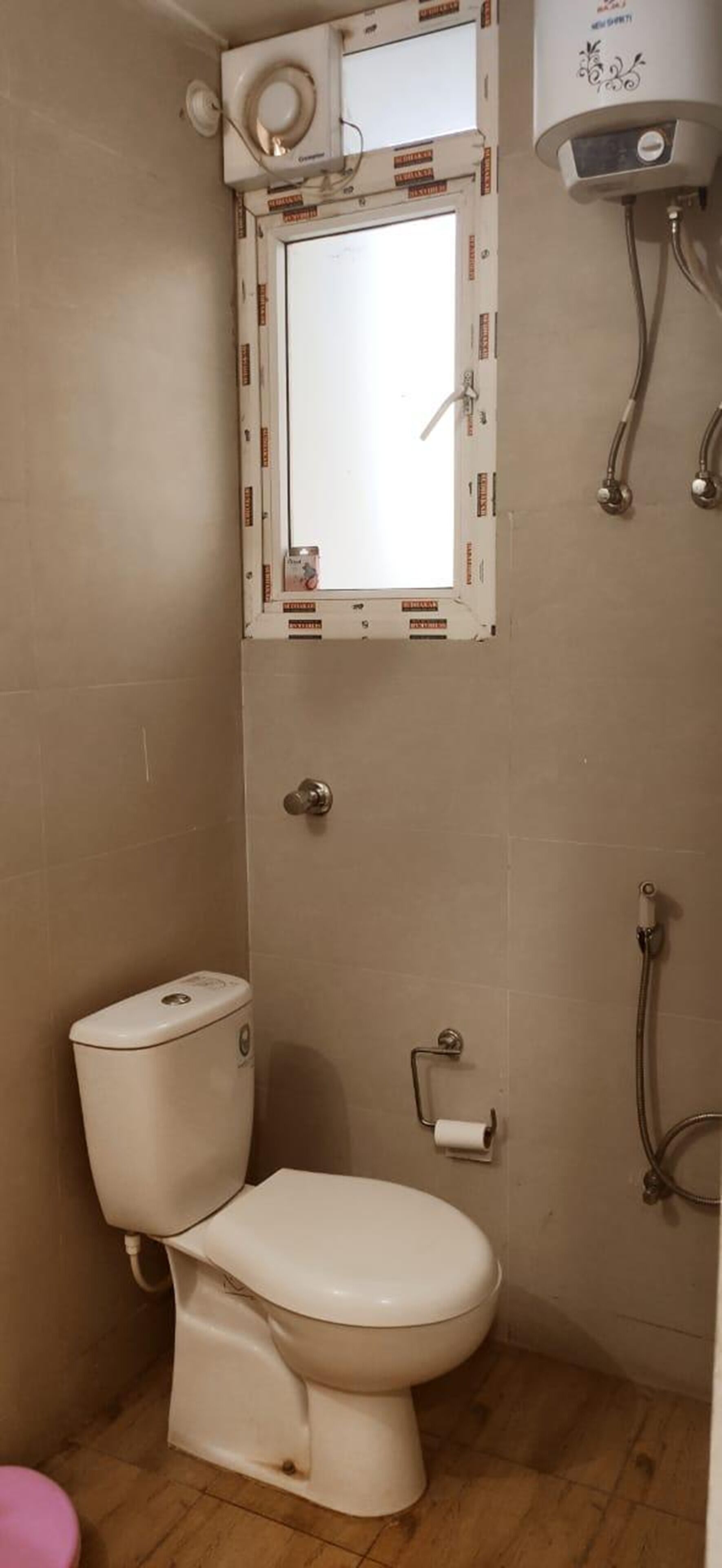 A bathroom with a toilet, a shower, and a mirror.