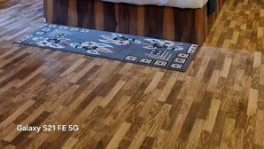 Een moderne hotelkamer met een houten vloer, een bed met blauwe kussens, een plafondventilator en een marmeren kunstwerk boven het bed.