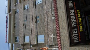 Een meerhoog gebouw met een bord waarop HOTEL PRANJAL INN staat, wat aangeeft dat het premium kamers en een ballroom lounge biedt.