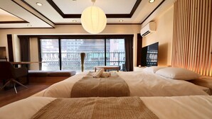 Quarto de hotel com duas camas de grande porte, uma mesa, uma cadeira, uma janela ampla com vista e um lustre.