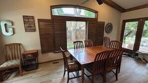 A dining room with a large wooden table and six chairs, a ceiling fan, and a window with shutters. - 6 bedrooms + office + fireplace + firepit + outdoor dining (Arvada)