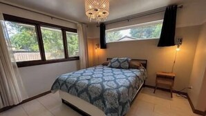 A bedroom with a bed, a nightstand, and a window with curtains. - 6 bedrooms + office + fireplace + firepit + outdoor dining (Arvada)