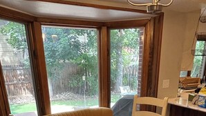 A dining area with a round table and four chairs, large windows with a view of a backyard, and a kitchen area with a countertop visible. - 6 bedrooms + office + fireplace + firepit + outdoor dining (Arvada)