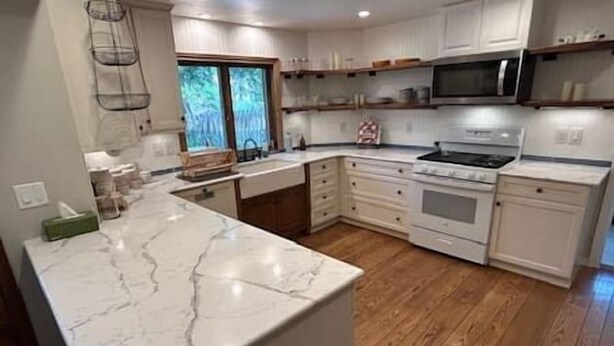 A kitchen with white cabinets, a marble countertop, a stainless steel microwave, and a stove. - 6 bedrooms + office + fireplace + firepit + outdoor dining (Arvada)