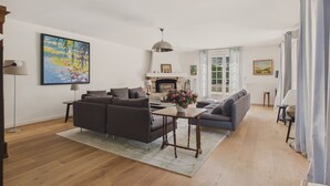 Ein geräumiges Wohnzimmer mit Kamin, Sofas und einem Esstisch.
