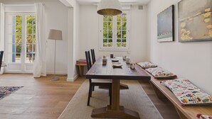 Ein Essbereich mit Holztisch, Bänken und einem großen Fenster mit Blick auf Grünflächen.