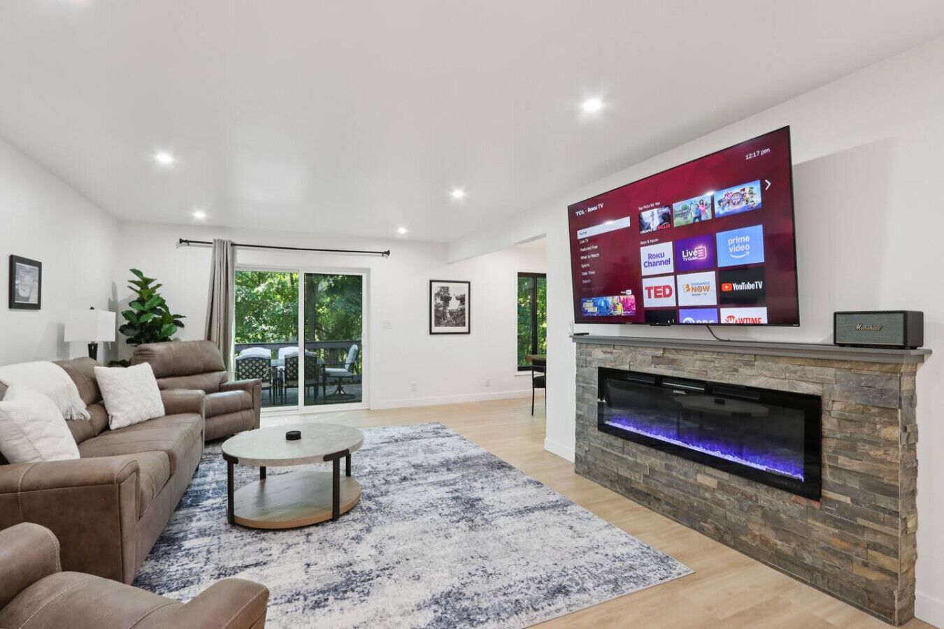 A modern living room with a flat-screen TV, a fireplace, and a sofa.