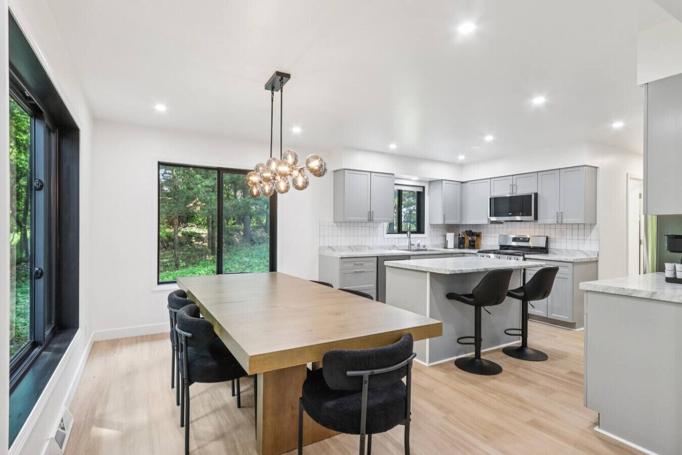 Una cocina moderna con una isla grande, taburetes de bar y una mesa de comedor con sillas.