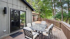 A deck with a glass door leading to a patio area, furnished with a table and chairs.