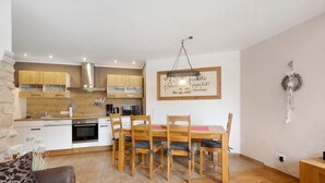Une cuisine moderne avec des meubles de rangement en bois, une table à manger avec des chaises et un luminaire suspendu.