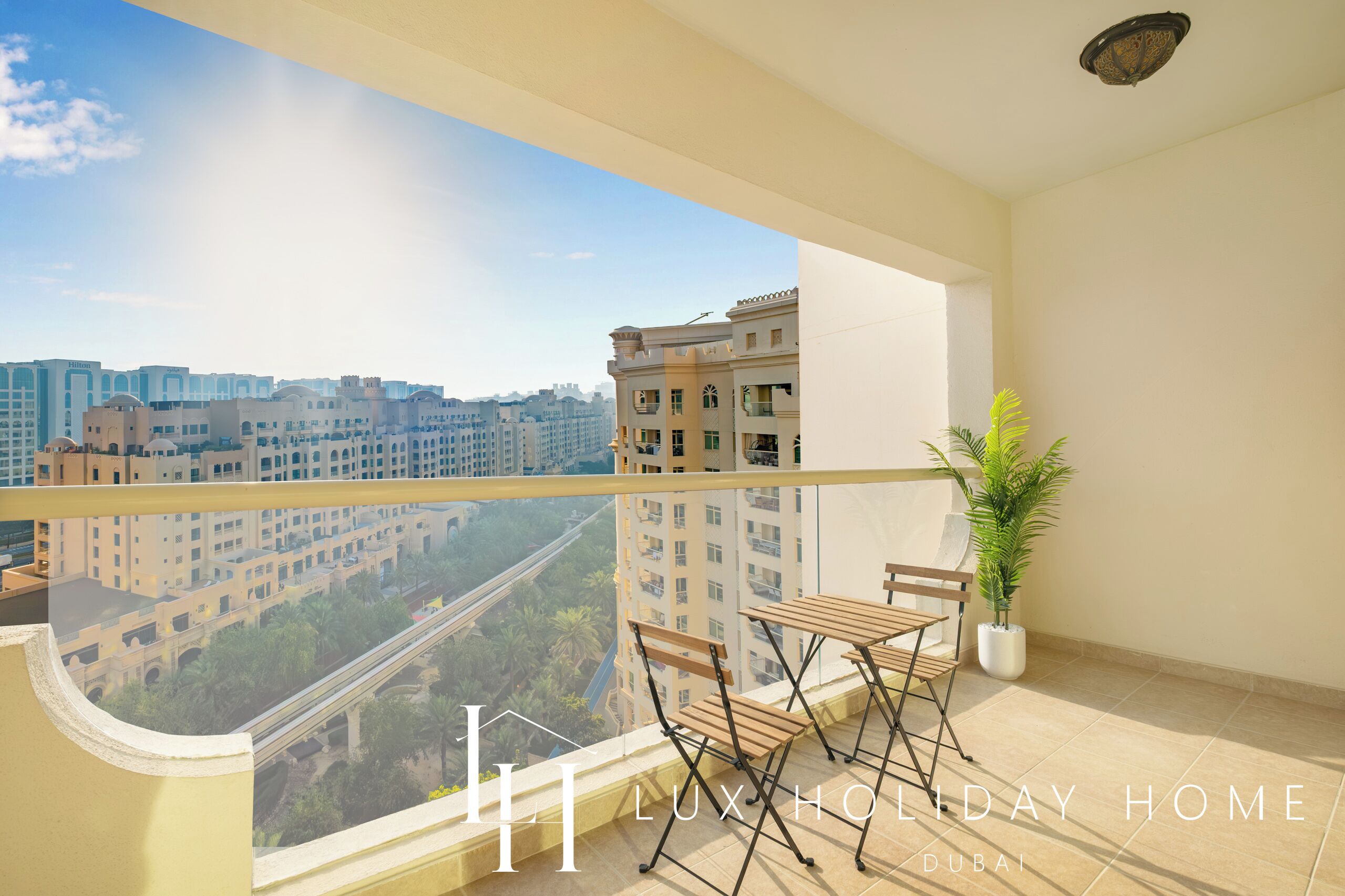 Un balcón con vista a la ciudad, una planta en maceta, y una mesa y sillas de madera.