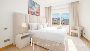 Camera d'hotel moderna con un letto grande, un comodino, una lampada, una sedia e vista sulla città dalla finestra.