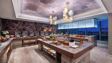 A modern hotel lobby with a marble reception desk, a high ceiling with a unique design, and a view of the city at night.