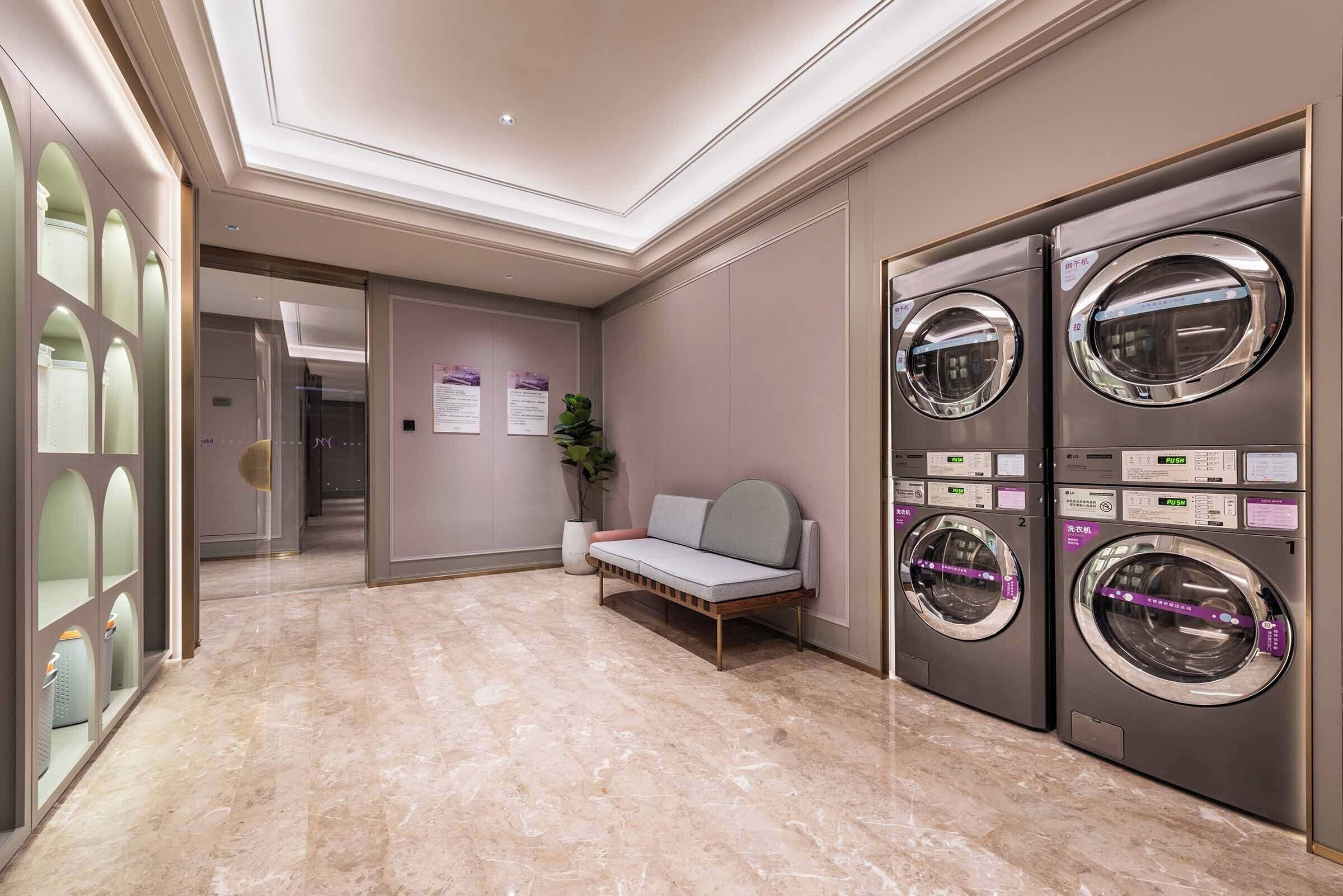 Un vestíbulo de hotel con piso de mármol, un sofá y dos lavadoras empotradas.