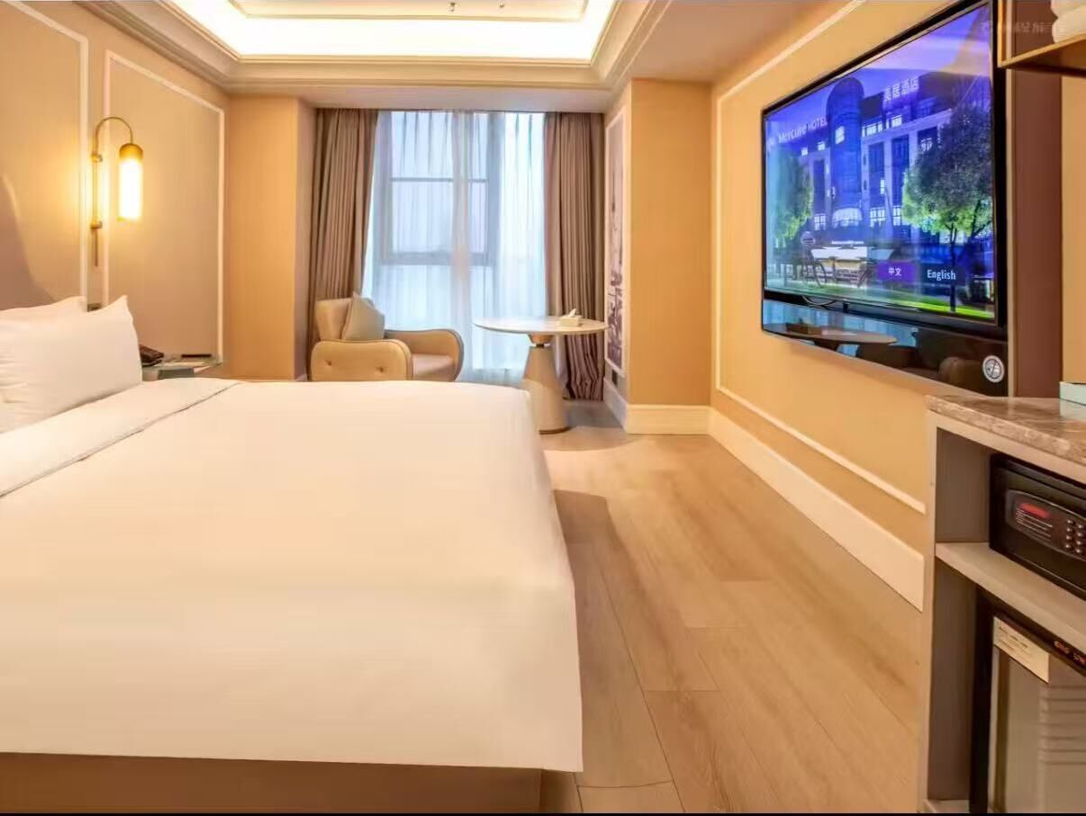 A hotel room with a large bed, a television, a desk, and a chair.