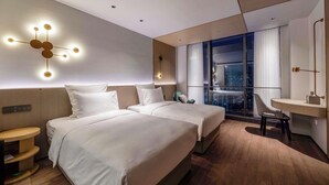 A modern hotel room with two beds, a desk, a chair, and a city view. - Novotel Kunshan East (Suzhou)