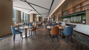 Een modern restaurant met hoge plafonds, grote ramen en een bar.