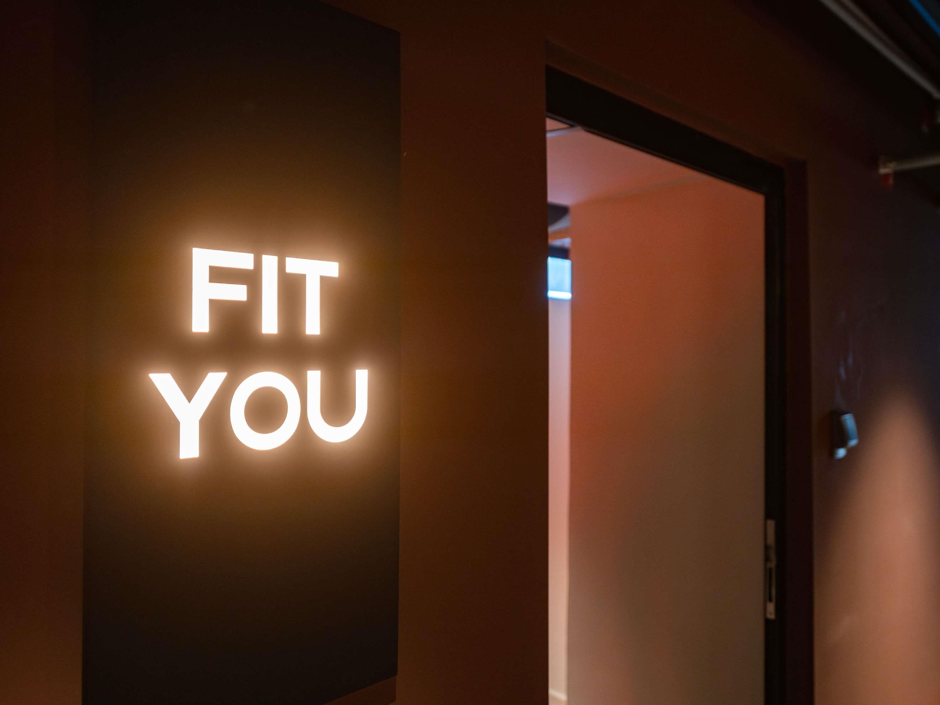 Un pasillo con un letrero que dice 'FIT YOU' iluminado en blanco.