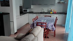 Una cocina moderna con armarios grises, una mesa de comedor con sillas y un sofá en la sala.