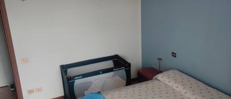 Una habitación pequeña y sencilla con una cama, una mesita y una silla.