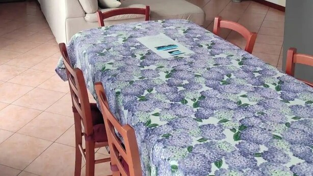 Una sala de estar con sofá, televisión y mesa de comedor con sillas.