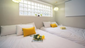 Une chambre d’hôtel avec deux lits, du linge de lit blanc, des oreillers jaunes, une fenêtre donnant sur un paysage agréable et un tableau blanc fixé au mur.