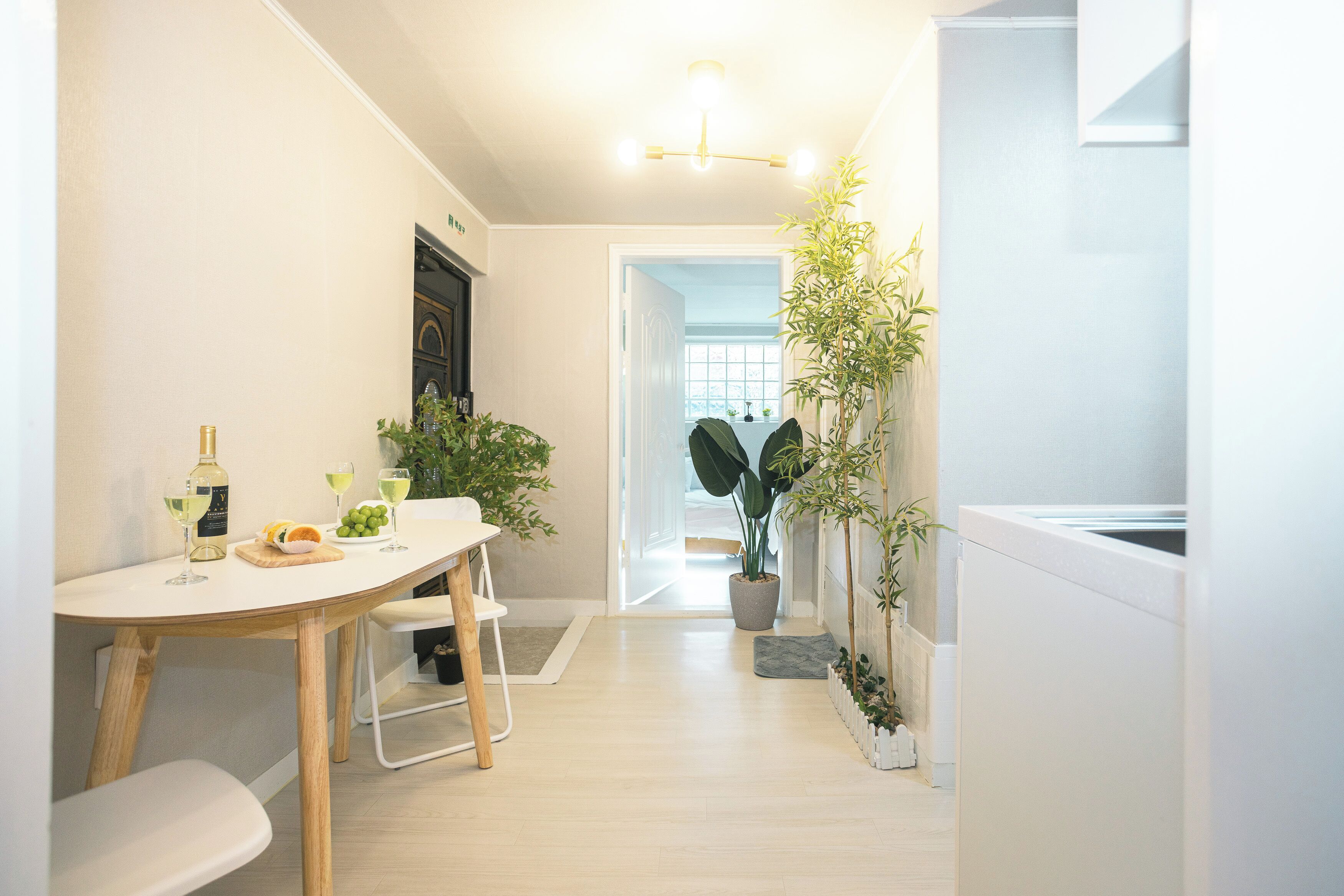 A modern kitchen with a dining area, featuring a wooden table, chairs, and potted plants.