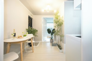 A modern kitchen with a dining area, featuring a wooden table, chairs, and potted plants.