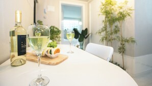 Une table à manger avec une bouteille de vin blanc, un verre de vin et une assiette de nourriture.