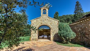 A stone building with a bell tower, an arched entrance, and a small porch area.