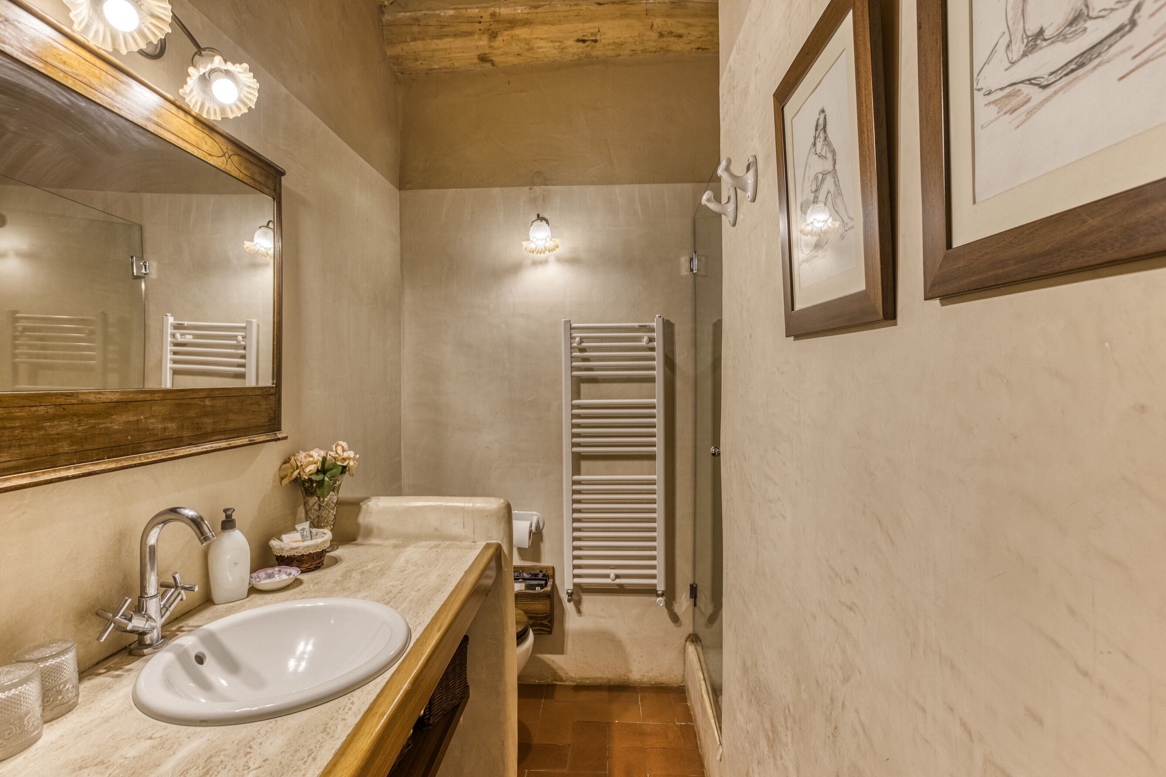 Uma casa de banho com lavatório, espelho, porta-toalhas e uma obra de arte emoldurada na parede.