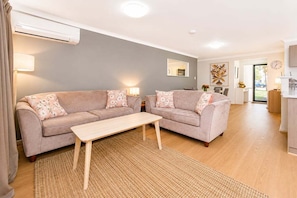 A living room with two sofas, a coffee table, and a kitchen area in the background.