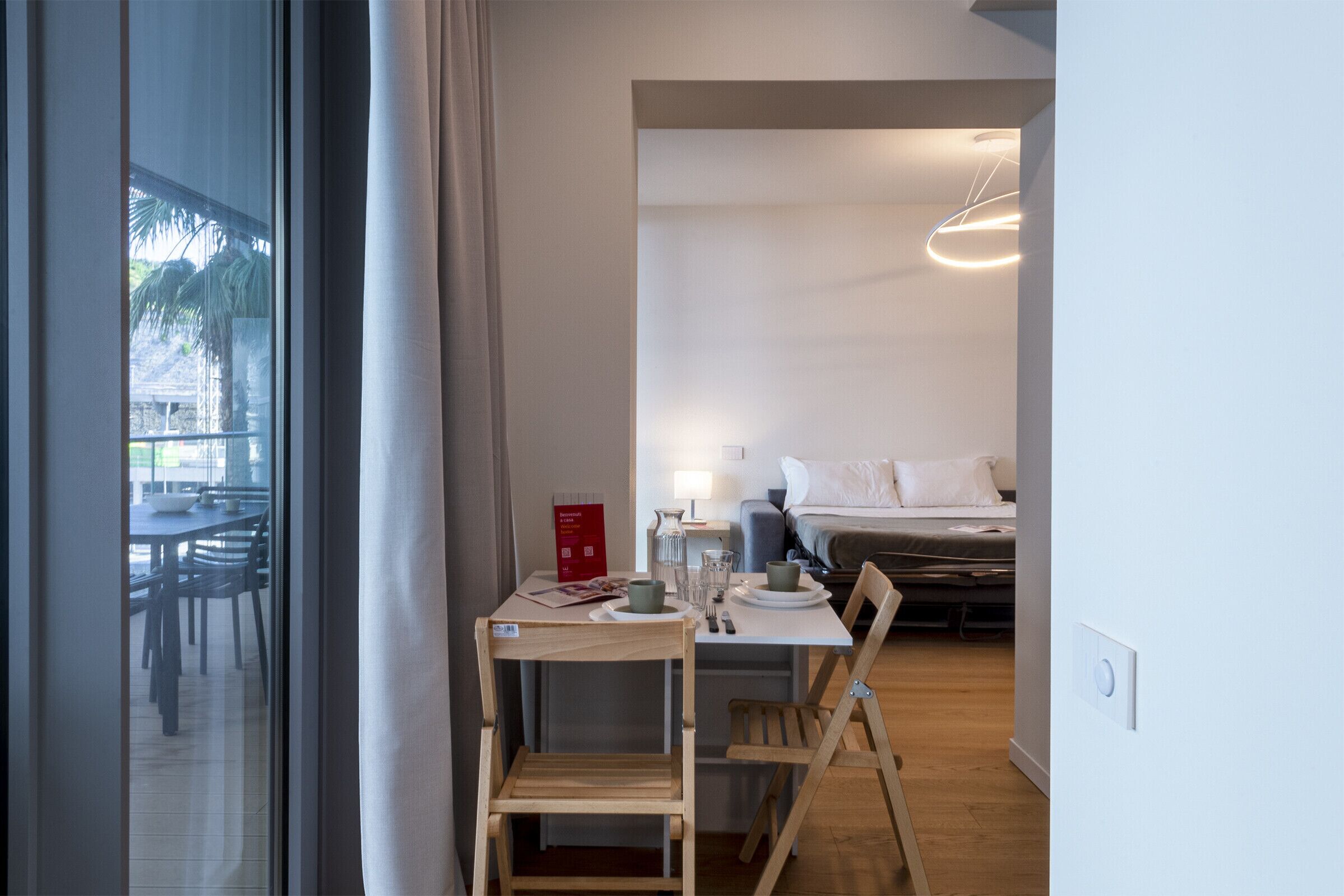 Habitación de hotel con comedor, cama y lámpara moderna.