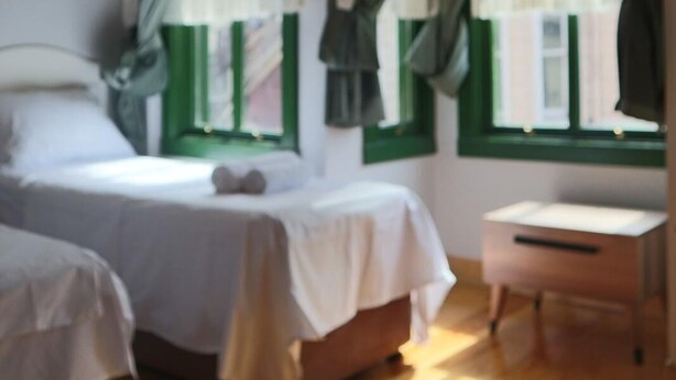 Un dormitorio con una cama, una mesita de noche y una ventana con cortinas.