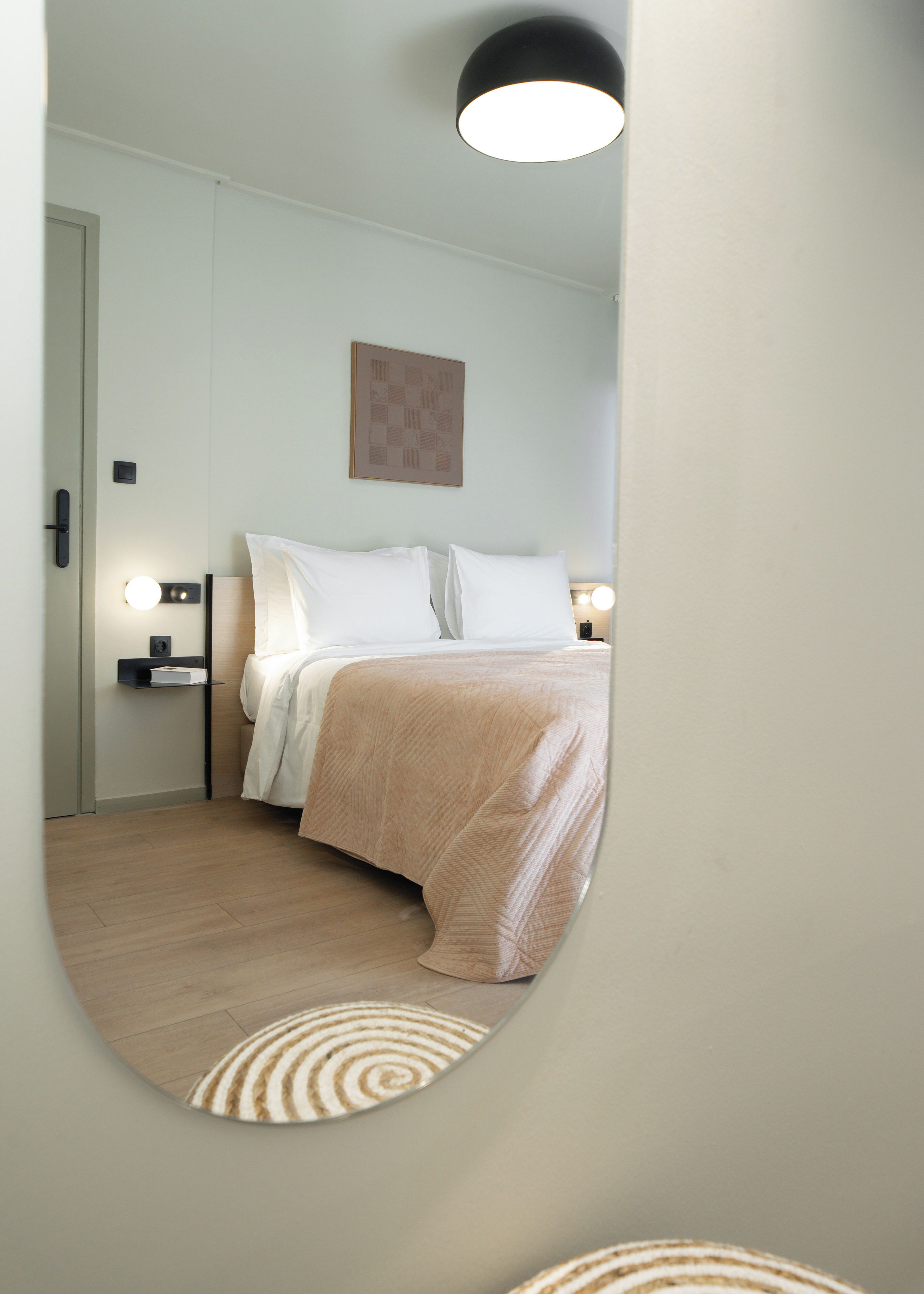 Un dormitorio con una cama, mesitas de noche, una lámpara de pared y un cuadro enmarcado.