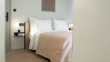 Un dormitorio con una cama, mesitas de noche, una lámpara de pared y un cuadro enmarcado.