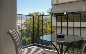 Un balcón con una mesa de vidrio y una silla a rayas.