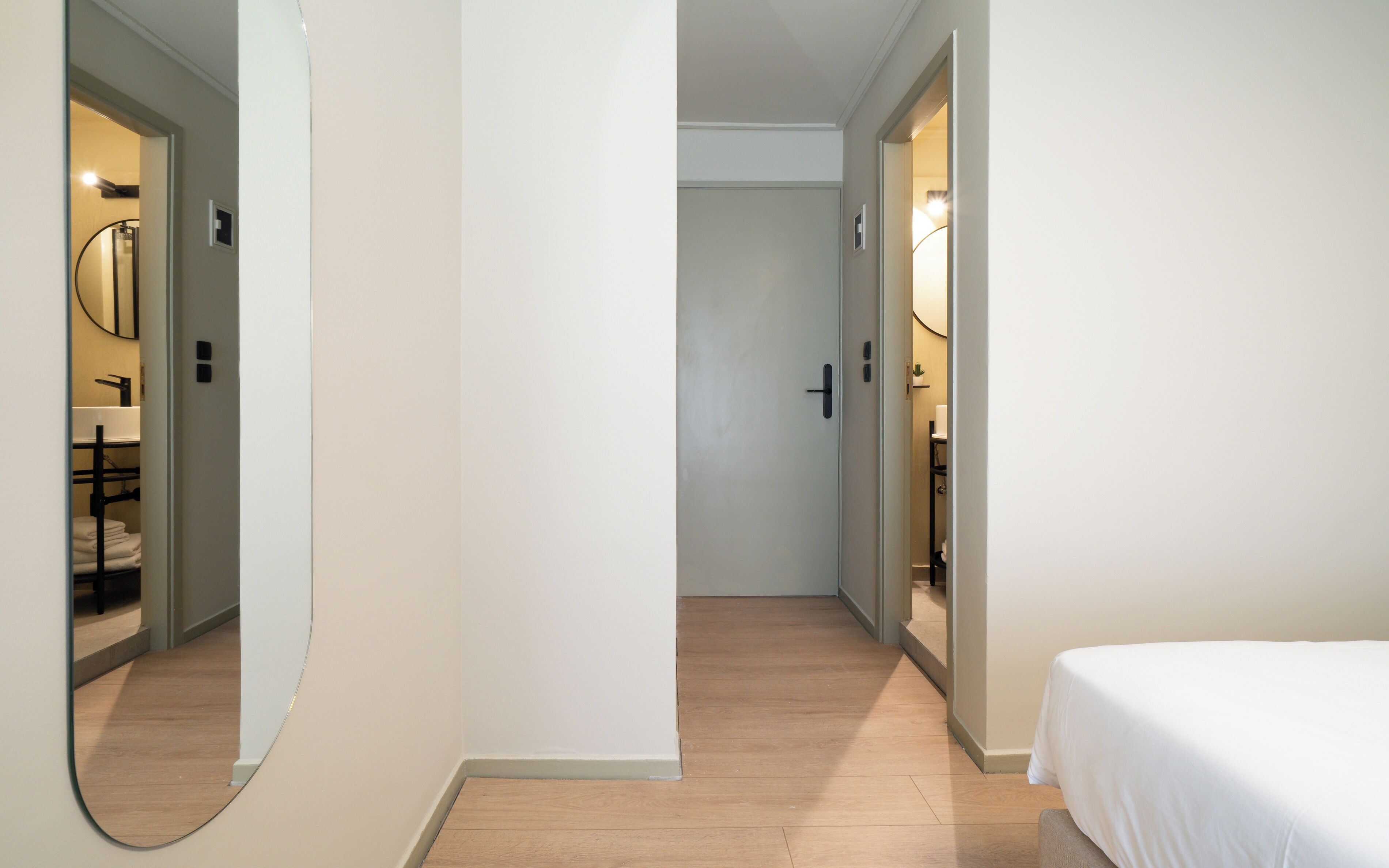 A hotel room with a bed, a mirror, and a bathroom visible through an open door.