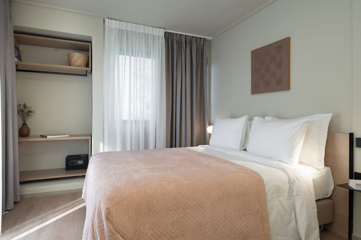 Una habitación de hotel con una cama, una repisa con un florero y un cuadro en la pared.