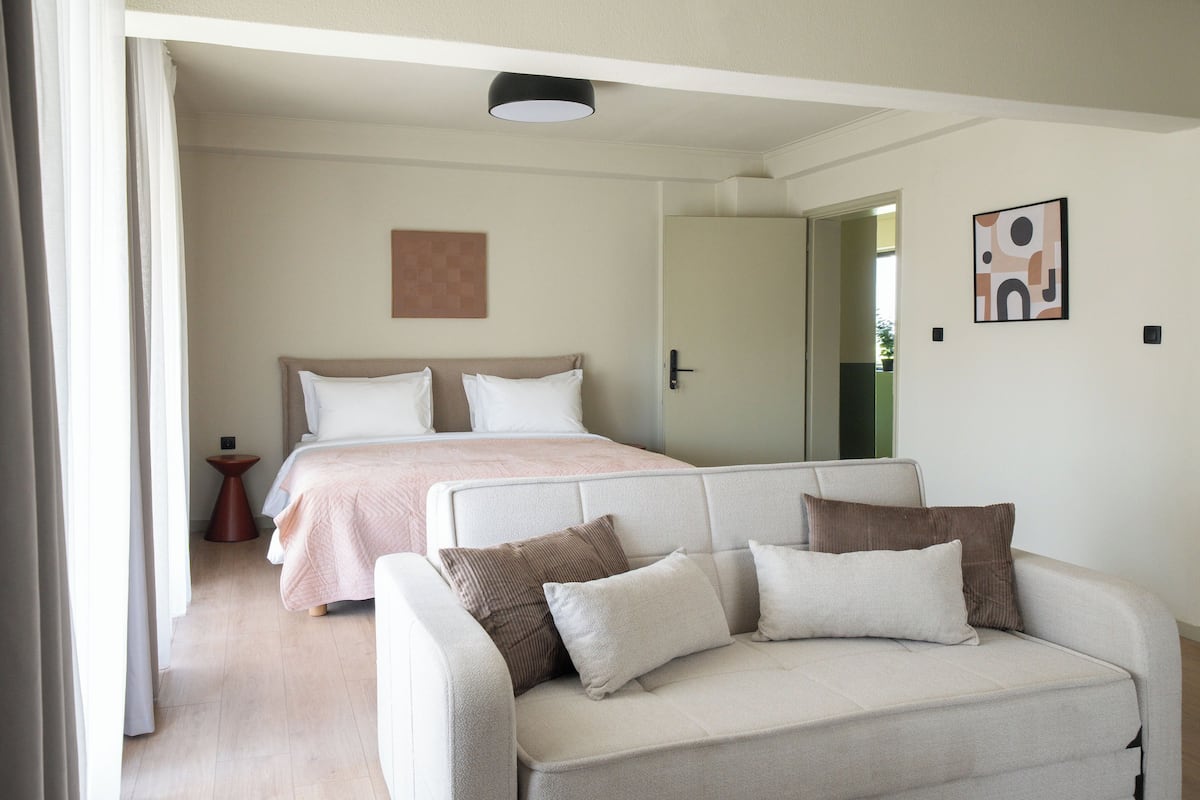 Un dormitorio moderno con una cama, un sofá y una puerta que da a otra habitación.