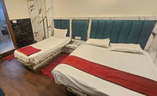 A hotel room with two single beds, each with a red blanket, white pillows, and a marble-patterned headboard.