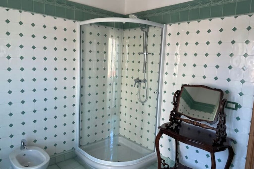 Een badkamer met een douchecabine, een wastafel en een spiegel met houten lijst.
