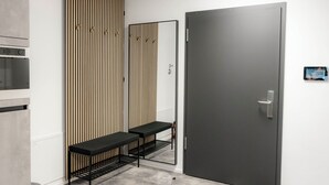 Een moderne badkamer met een grote spiegel, een donkere deur en een bankje.