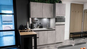 Een moderne keuken met grijze kastjes, een houten tafel en een bankje. Er staan flessen op de tafel en een bordje met de tekst 'START'.