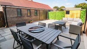 A patio area with a table and chairs, a sofa, and a wooden fence.