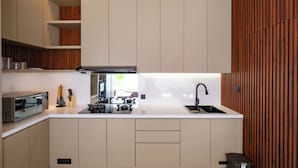 A modern kitchen with built-in appliances, a sink, and wooden paneling. - The Moringa Bukit Villas (Kutuh)