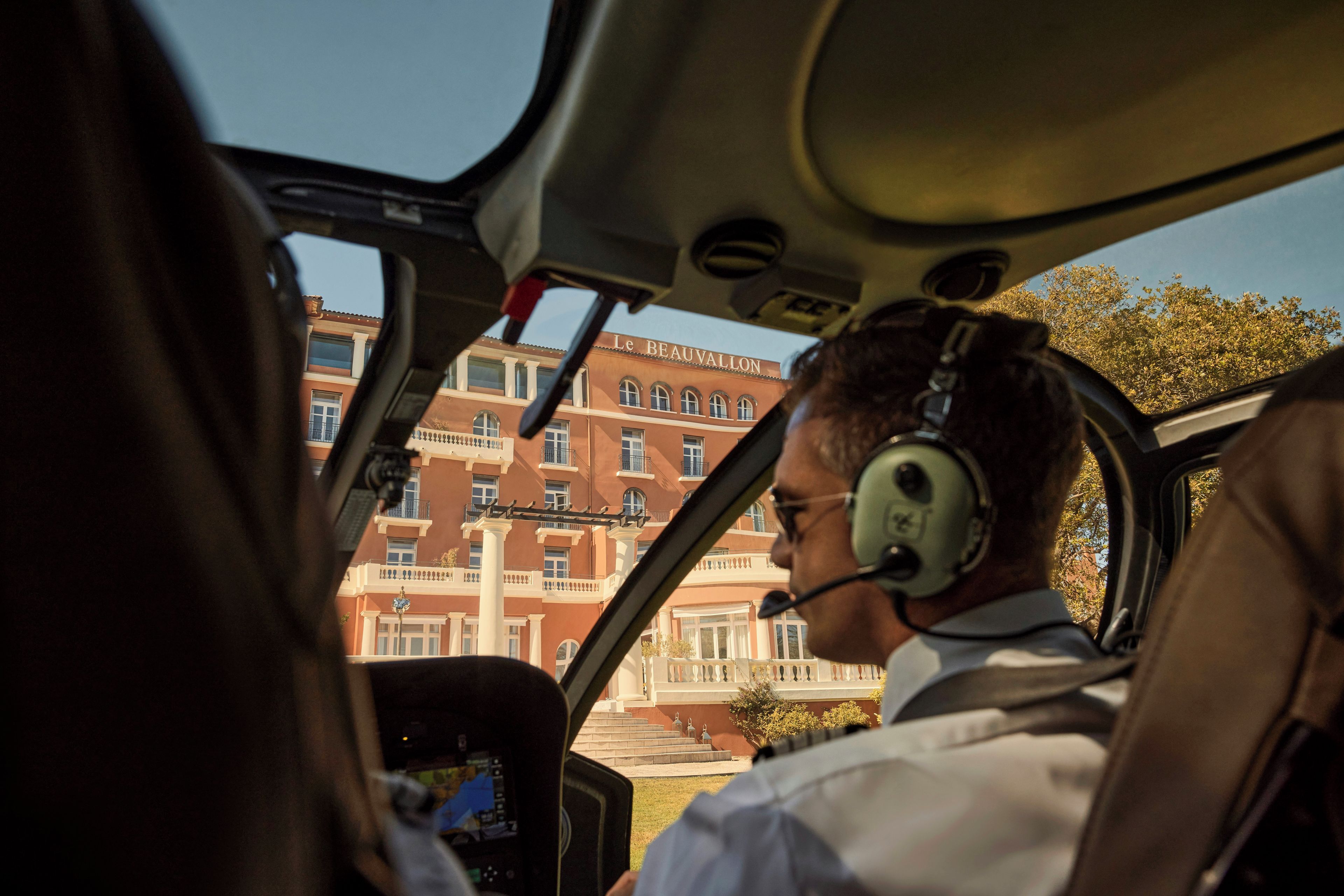 Un piloto dentro de la cabina de un avión, con vista a un edificio con columnas y balcones.