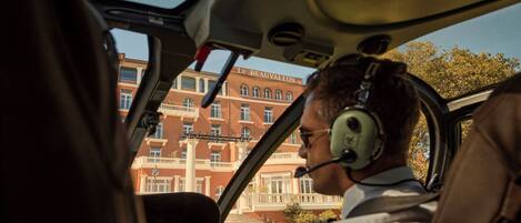 Un piloto dentro de la cabina de un avión, con vista a un edificio con columnas y balcones.